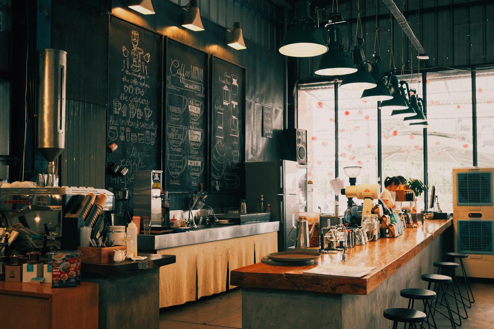 Café-Innenraum mit Kaffeemenü auf Schiefertafel, Barista im Hintergrund.
