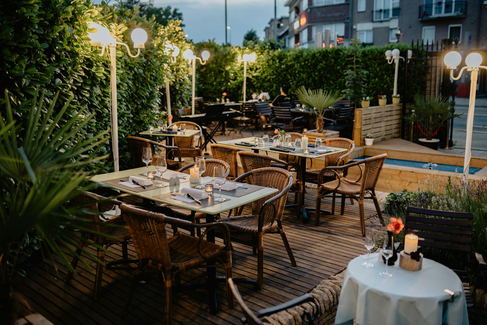 Restaurant-Terrasse am Abend mit Kerzen und warmem Lichtbogen, bereit für den Service.