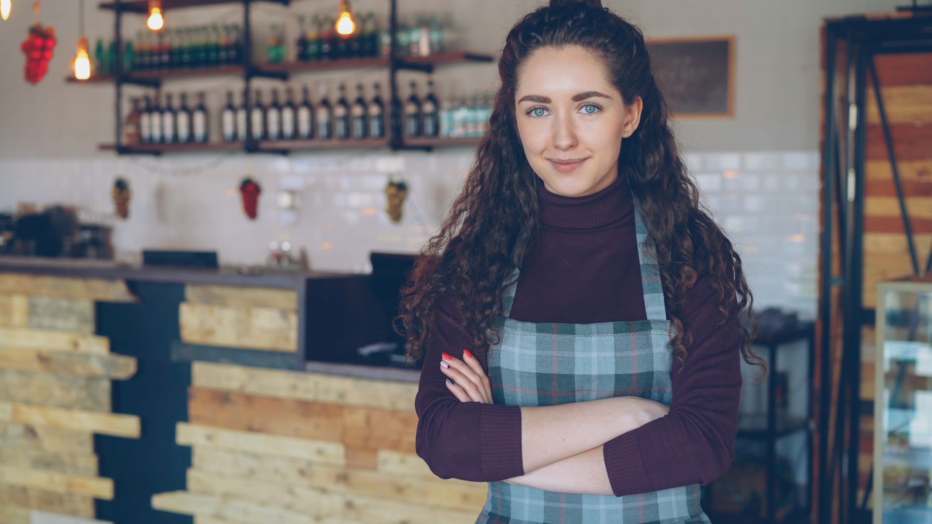 Gastronom steht mit verschränkten Armen im eigenen rustikalen Café.