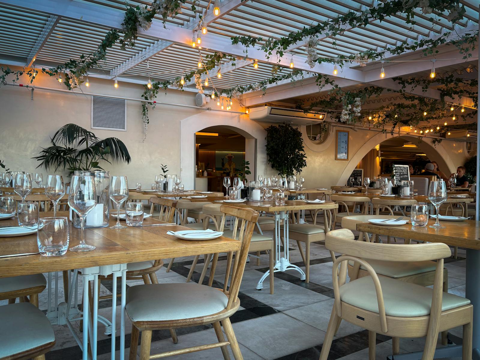 Elegantes Restaurant mit Holzmöbeln, warmem Licht und gedeckten Tischen, bereit für den Abendservice.
