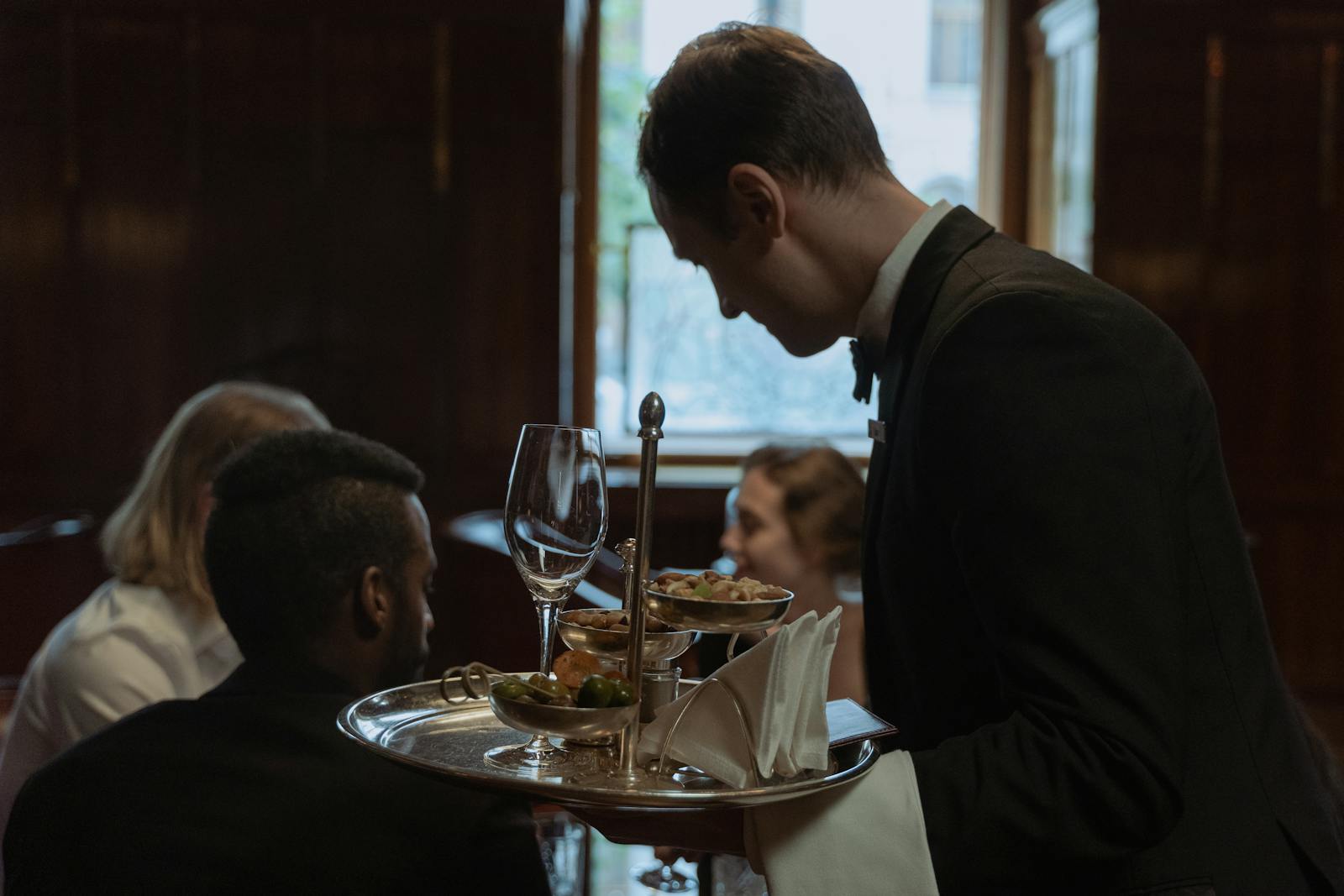Servicekraft bedient Gäste an einem besetzten Restauranttisch.